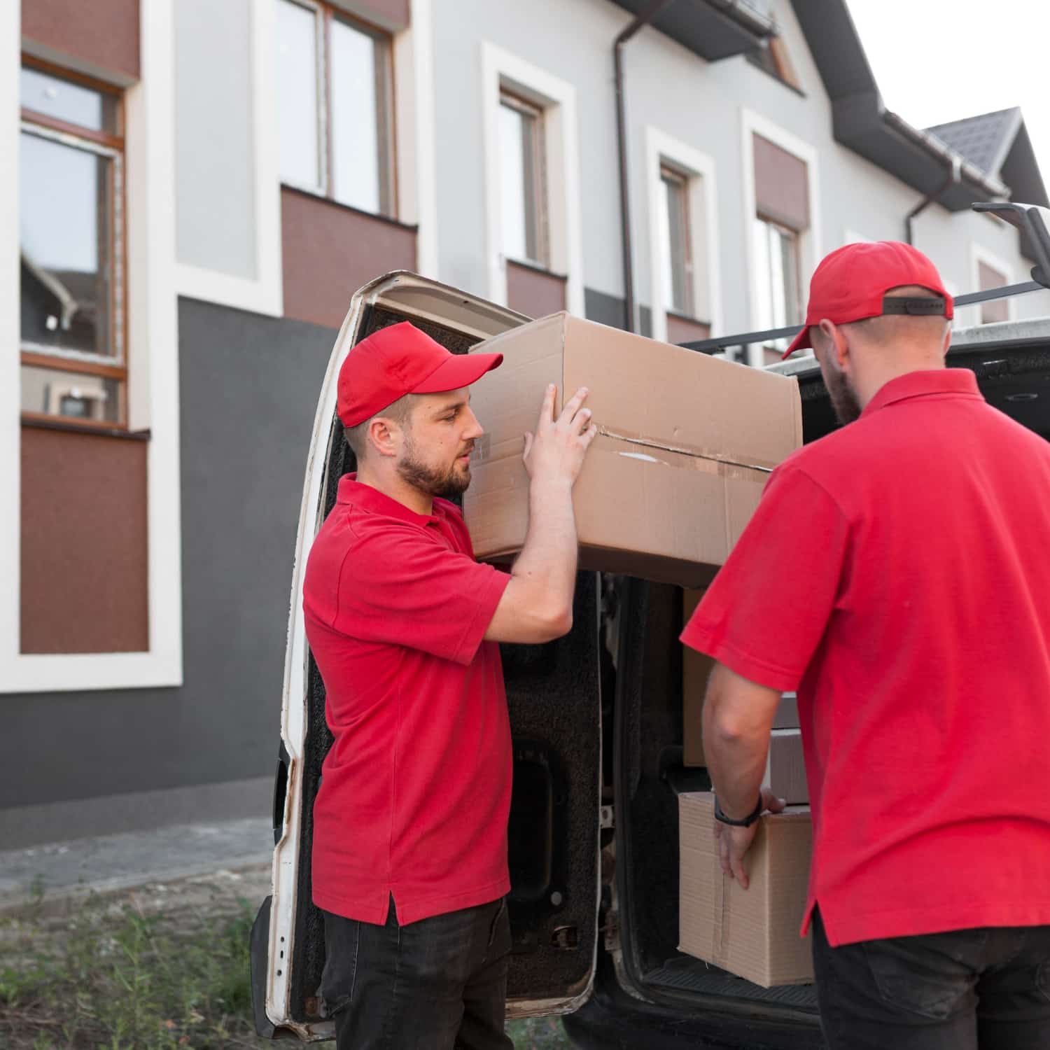 Mitarbeiter vom Umzugsunternehmen Schaumburg – Umzugsmeister Wolters – beim Tragen von Umzugskartons vor einem Haus.
